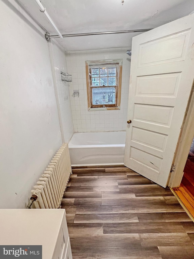 bathroom with hardwood / wood-style floors and tiled shower / bath