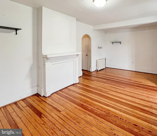 empty room with radiator heating unit and light hardwood / wood-style flooring