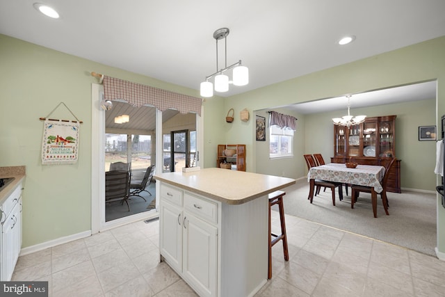 kitchen with light carpet, white cabinets, pendant lighting, and a kitchen island