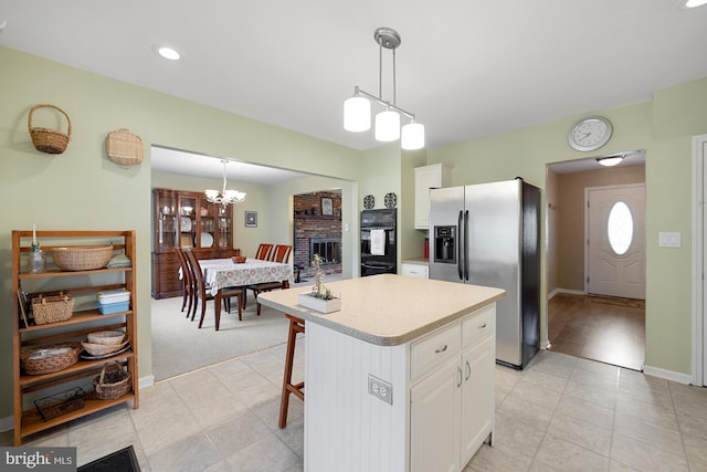 kitchen with stainless steel fridge with ice dispenser, a kitchen island, pendant lighting, and white cabinets