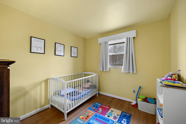 bedroom featuring wood-type flooring and a crib