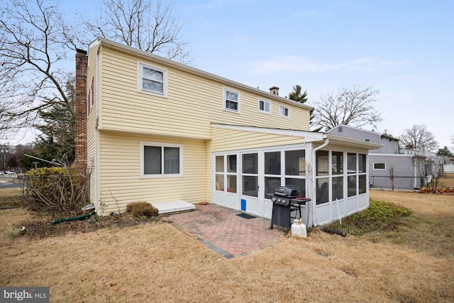 rear view of house featuring a patio area, a sunroom, and a lawn