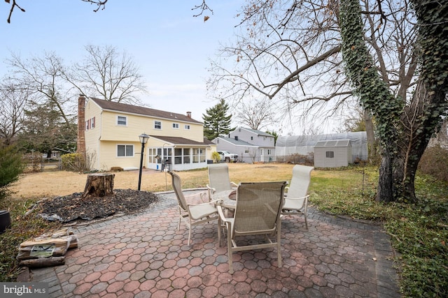 view of patio featuring a storage unit and a sunroom