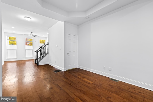 interior space with dark hardwood / wood-style floors, ceiling fan, and a tray ceiling