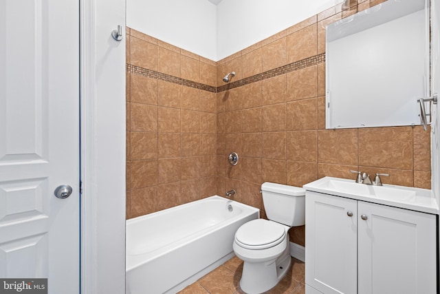 full bathroom with vanity, tile patterned flooring, tiled shower / bath combo, toilet, and tile walls