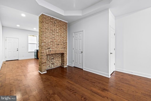 unfurnished living room with wood-type flooring and a tray ceiling