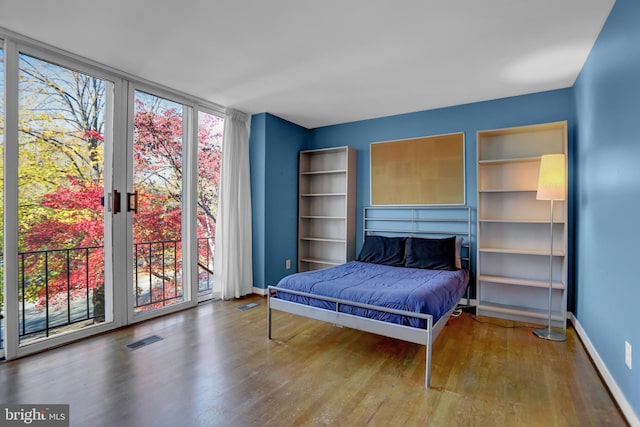 bedroom with wood-type flooring, access to outside, and multiple windows