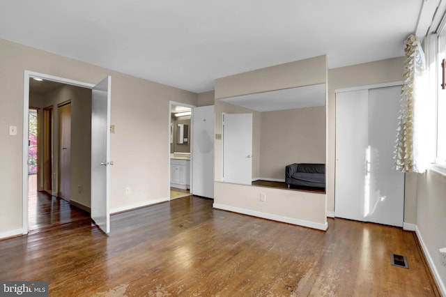 unfurnished living room featuring a wealth of natural light and dark wood-type flooring