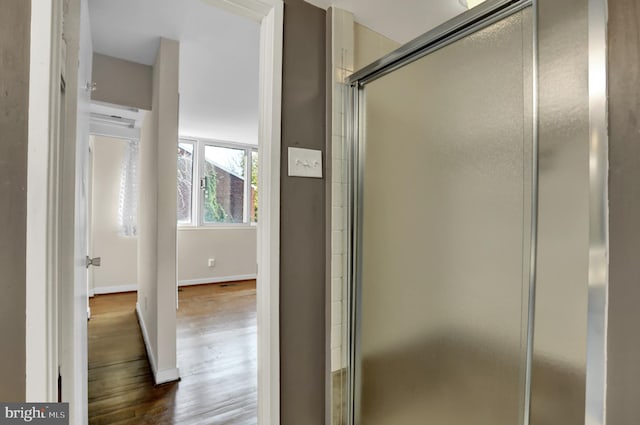 bathroom with wood-type flooring and a shower with shower door