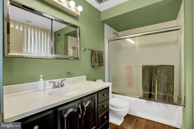 full bathroom featuring combined bath / shower with glass door, hardwood / wood-style floors, vanity, and toilet