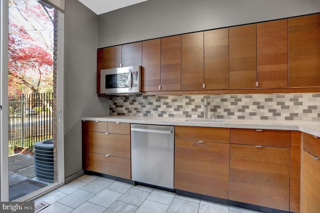 251 W Lafayette Ave, Baltimore, MD 21217 - kitchen with stainless steel appliances, a sink, backsplash, brown cabinets, and healthy amount of natural light