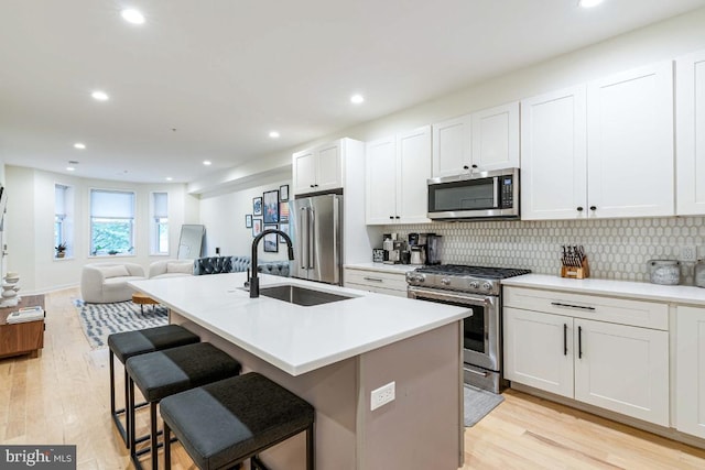 kitchen featuring white cabinetry, a kitchen island with sink, light wood-type flooring, and appliances with stainless steel finishes