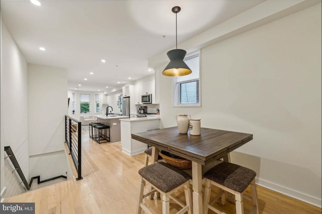 dining space with light wood-type flooring and sink