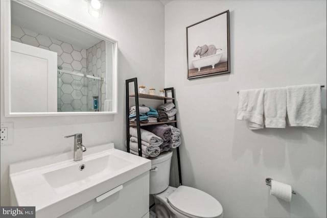 bathroom featuring toilet, a shower with shower door, and sink