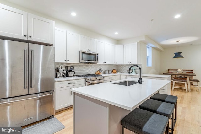 kitchen featuring pendant lighting, sink, a breakfast bar area, light hardwood / wood-style floors, and stainless steel appliances