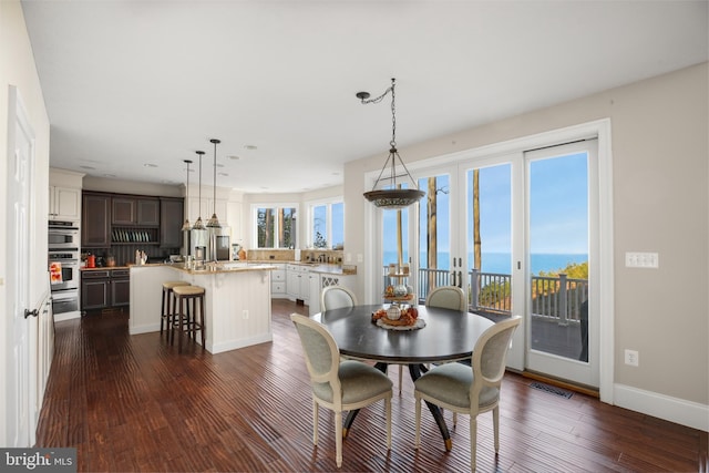 dining area featuring dark wood-type flooring, a water view, visible vents, baseboards, and french doors