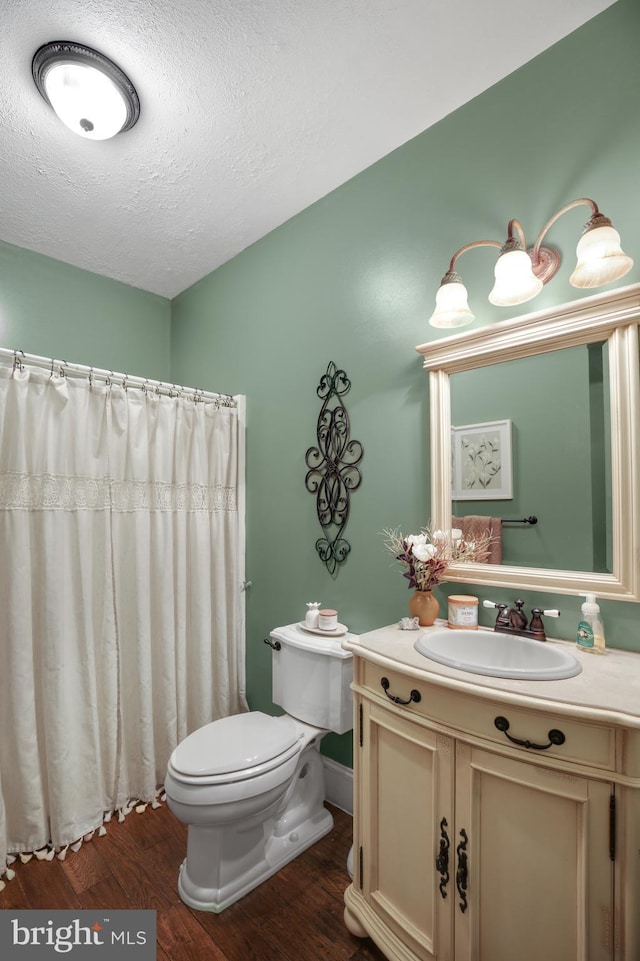 bathroom featuring toilet, vanity, a textured ceiling, wood finished floors, and a shower with curtain