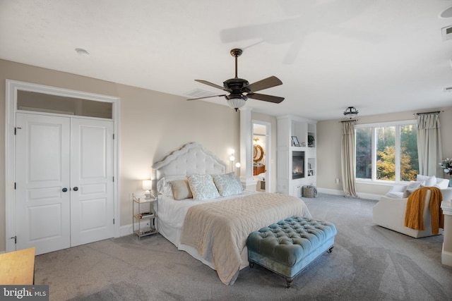 bedroom with carpet floors, a large fireplace, visible vents, and baseboards