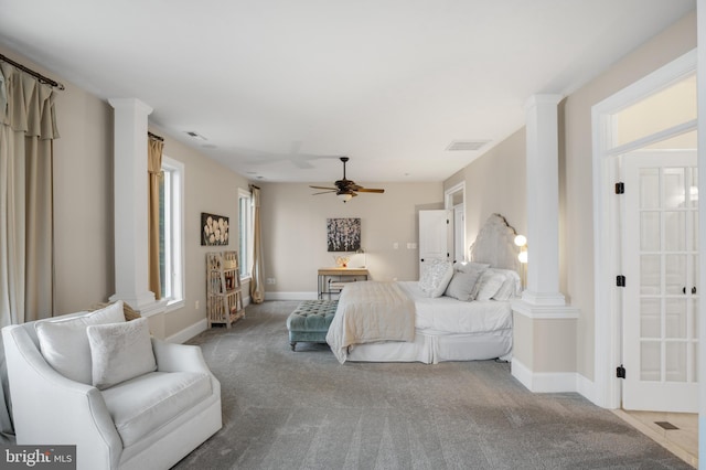 carpeted bedroom with a ceiling fan, decorative columns, visible vents, and baseboards