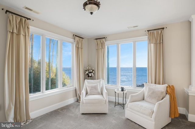 sitting room featuring visible vents, a water view, and baseboards