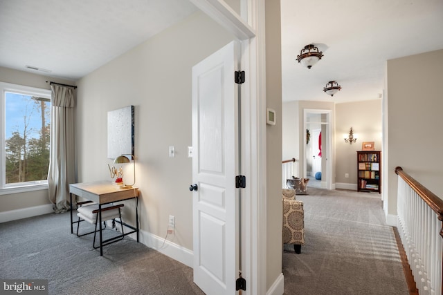 corridor with carpet floors, an upstairs landing, visible vents, and baseboards