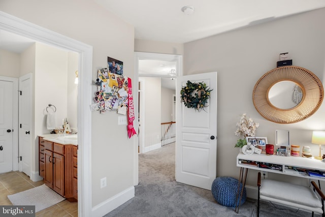 interior space featuring light carpet, light tile patterned floors, baseboards, and a sink