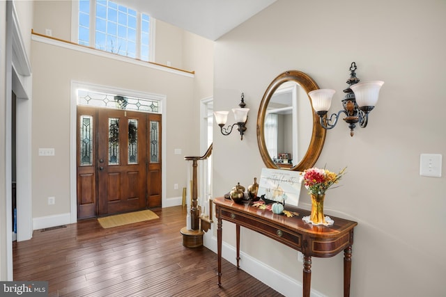 foyer entrance with wood-type flooring, visible vents, a notable chandelier, and baseboards