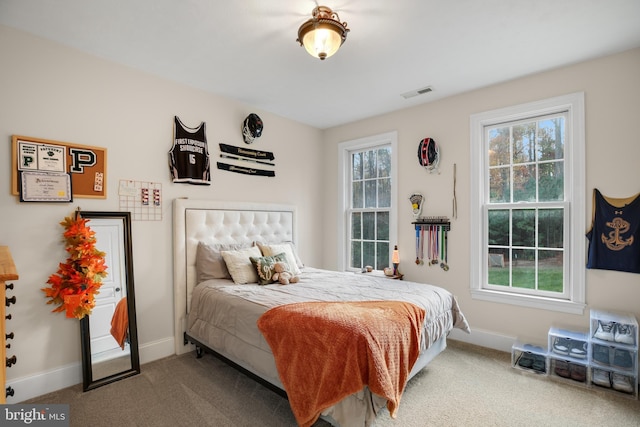 carpeted bedroom featuring multiple windows, visible vents, and baseboards