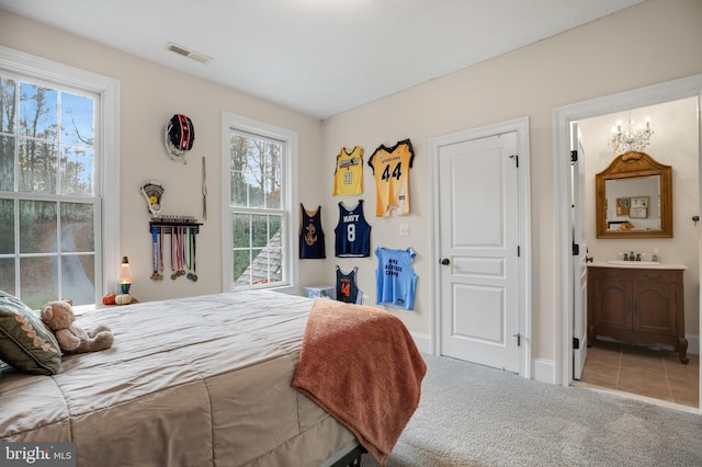 carpeted bedroom featuring connected bathroom, a sink, visible vents, baseboards, and an inviting chandelier