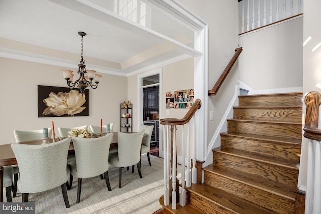 dining area with a tray ceiling, stairway, ornamental molding, wood finished floors, and a chandelier