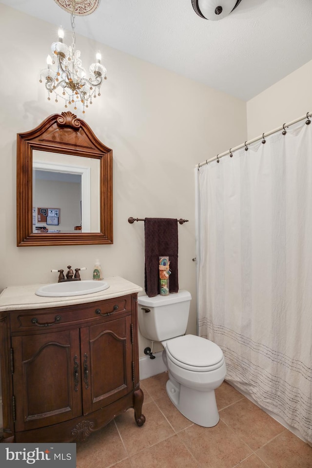 bathroom featuring tile patterned flooring, a notable chandelier, vanity, and toilet