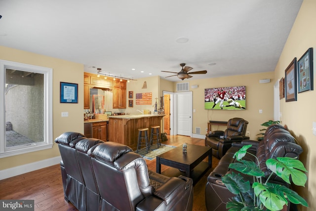 living room with a ceiling fan, wood-type flooring, visible vents, and baseboards