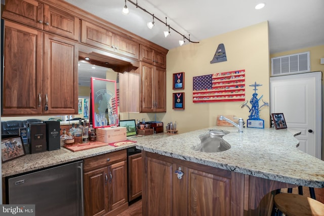 kitchen with light stone counters, a breakfast bar area, a peninsula, visible vents, and fridge