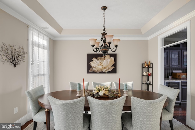 dining space with beverage cooler, wood finished floors, a tray ceiling, crown molding, and a notable chandelier