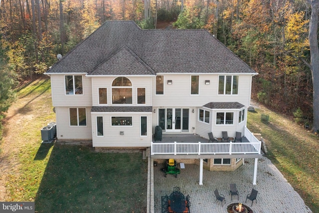 exterior space with a shingled roof, french doors, central AC, and a front lawn