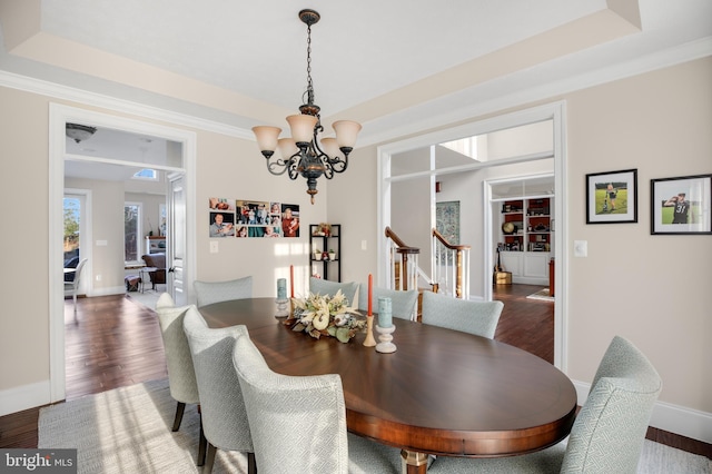 dining area with a chandelier, a tray ceiling, stairway, and wood finished floors