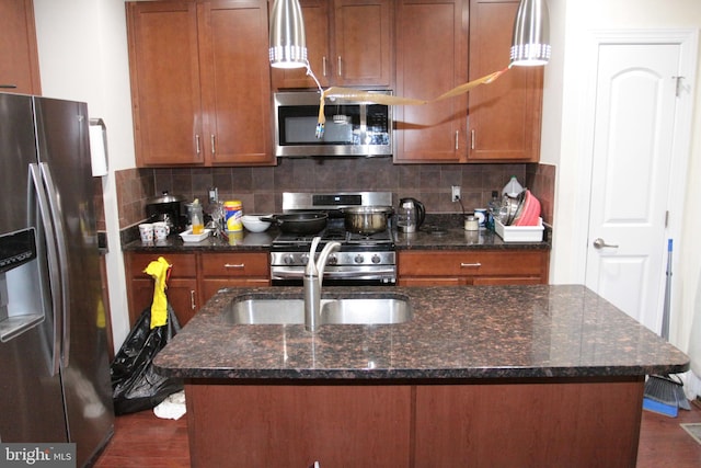 kitchen with dark stone counters, a kitchen island with sink, and stainless steel appliances