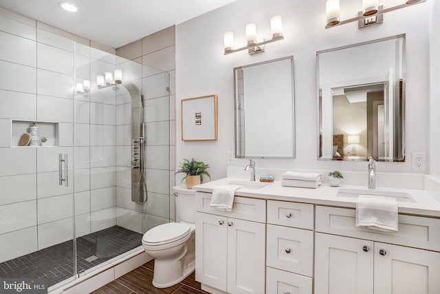 full bath with a stall shower, a sink, toilet, and double vanity