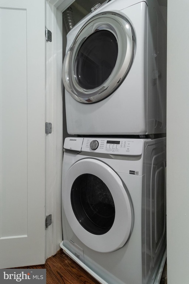 washroom featuring laundry area, dark wood-style flooring, and stacked washer / drying machine