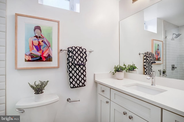 full bath featuring toilet, tiled shower, and vanity