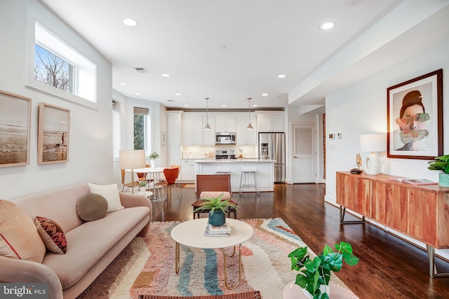 living room with dark wood-style floors, visible vents, and recessed lighting