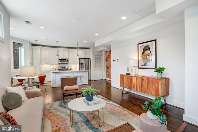 living area with dark wood-type flooring, recessed lighting, visible vents, and baseboards