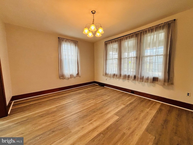 unfurnished room featuring a chandelier and hardwood / wood-style floors