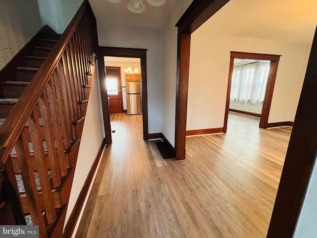 stairway with a healthy amount of sunlight, wood-type flooring, and a notable chandelier