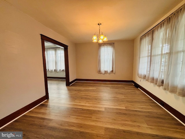 unfurnished dining area featuring wood-type flooring and an inviting chandelier