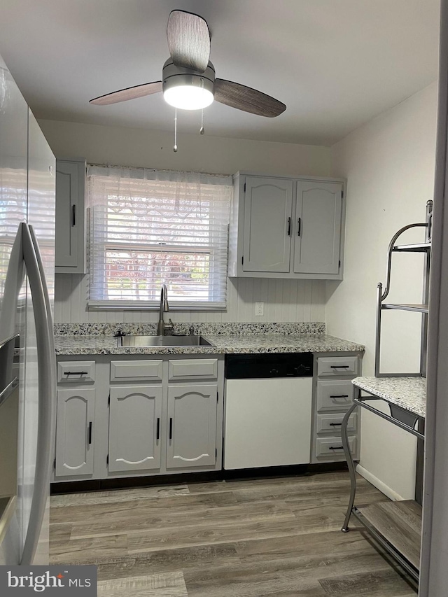 kitchen featuring ceiling fan, dishwasher, sink, light hardwood / wood-style flooring, and stainless steel fridge