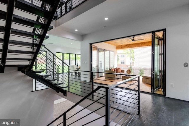 staircase with a wealth of natural light, hardwood / wood-style floors, and ceiling fan