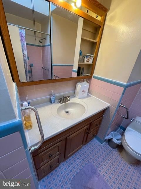 bathroom featuring tile patterned floors, walk in shower, vanity, tile walls, and toilet