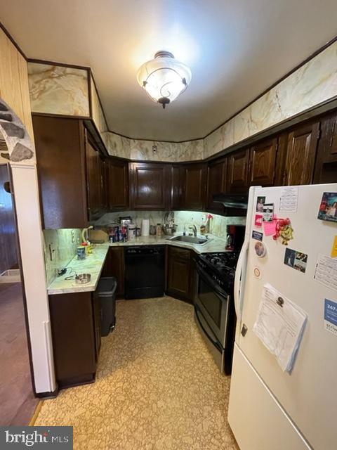 kitchen with dark brown cabinetry, stainless steel gas stove, dishwasher, sink, and white fridge