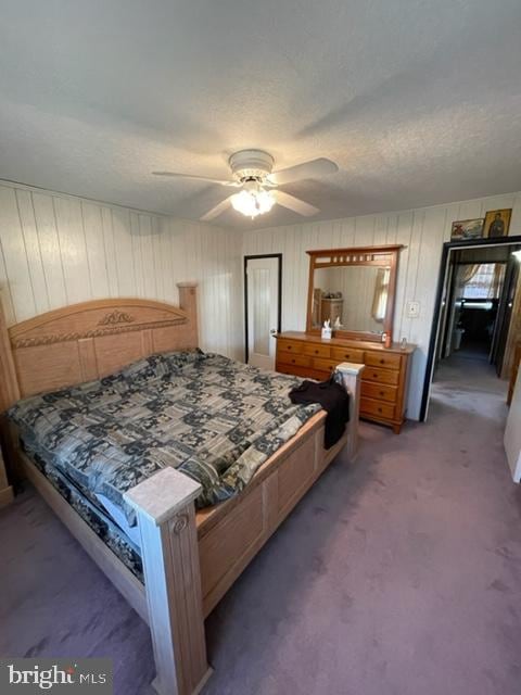 bedroom with dark colored carpet, ceiling fan, and a textured ceiling